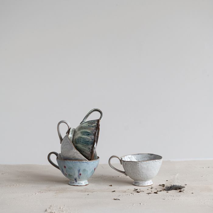 Set of ceramic teacups and a teapot on a light surface with a neutral background
