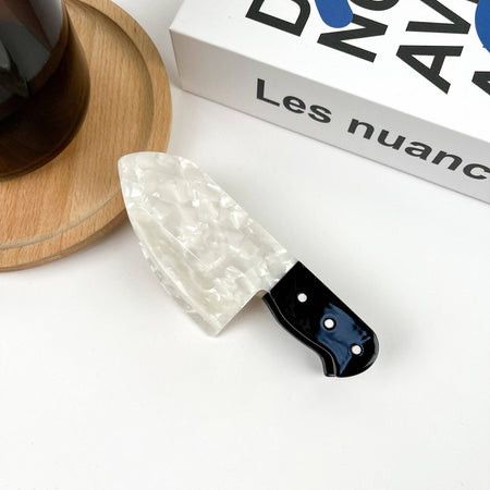 Decorative knife with a white blade and black handle on a white surface