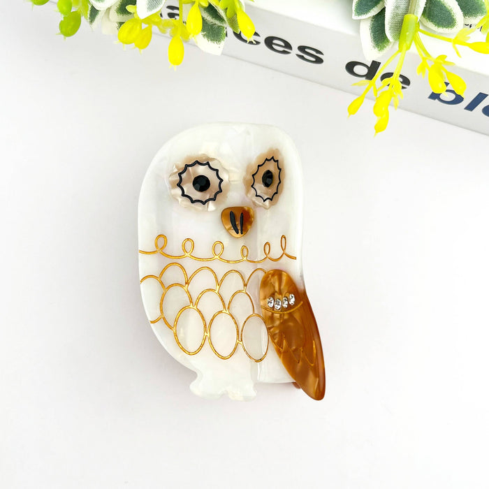 Decorative owl-shaped hair clip with gold accents on a white background