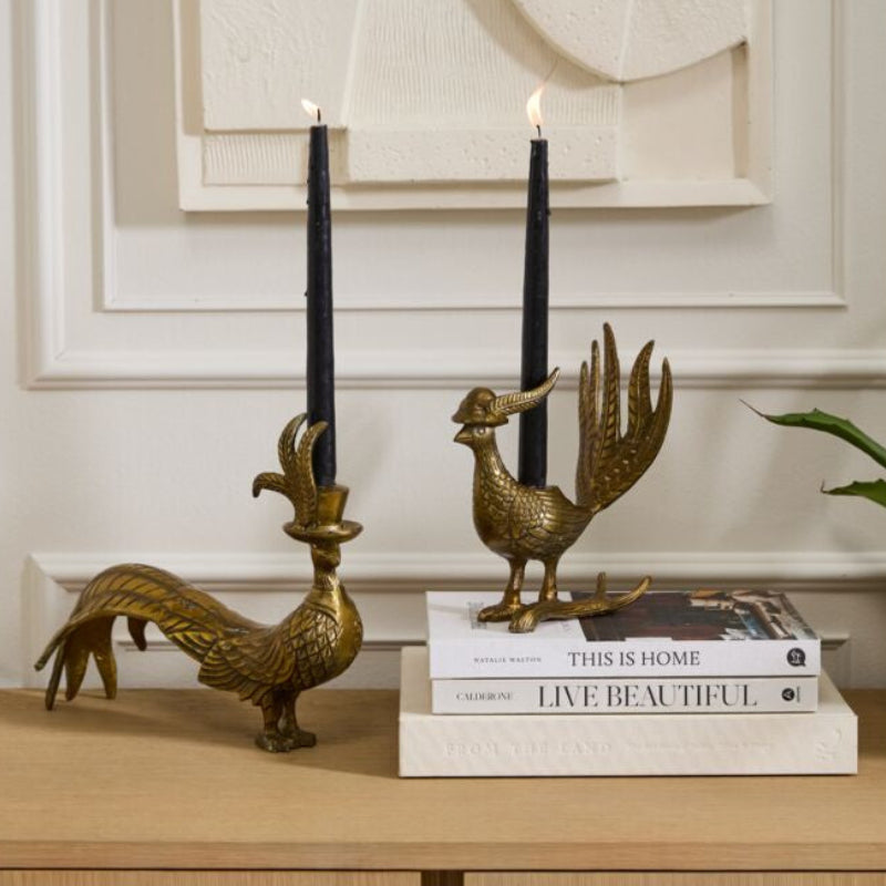 Decorative brass candlestick holders with black candles on a wooden surface.