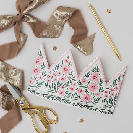 Floral-patterned paper crown with gold scissors and ribbons on a light background