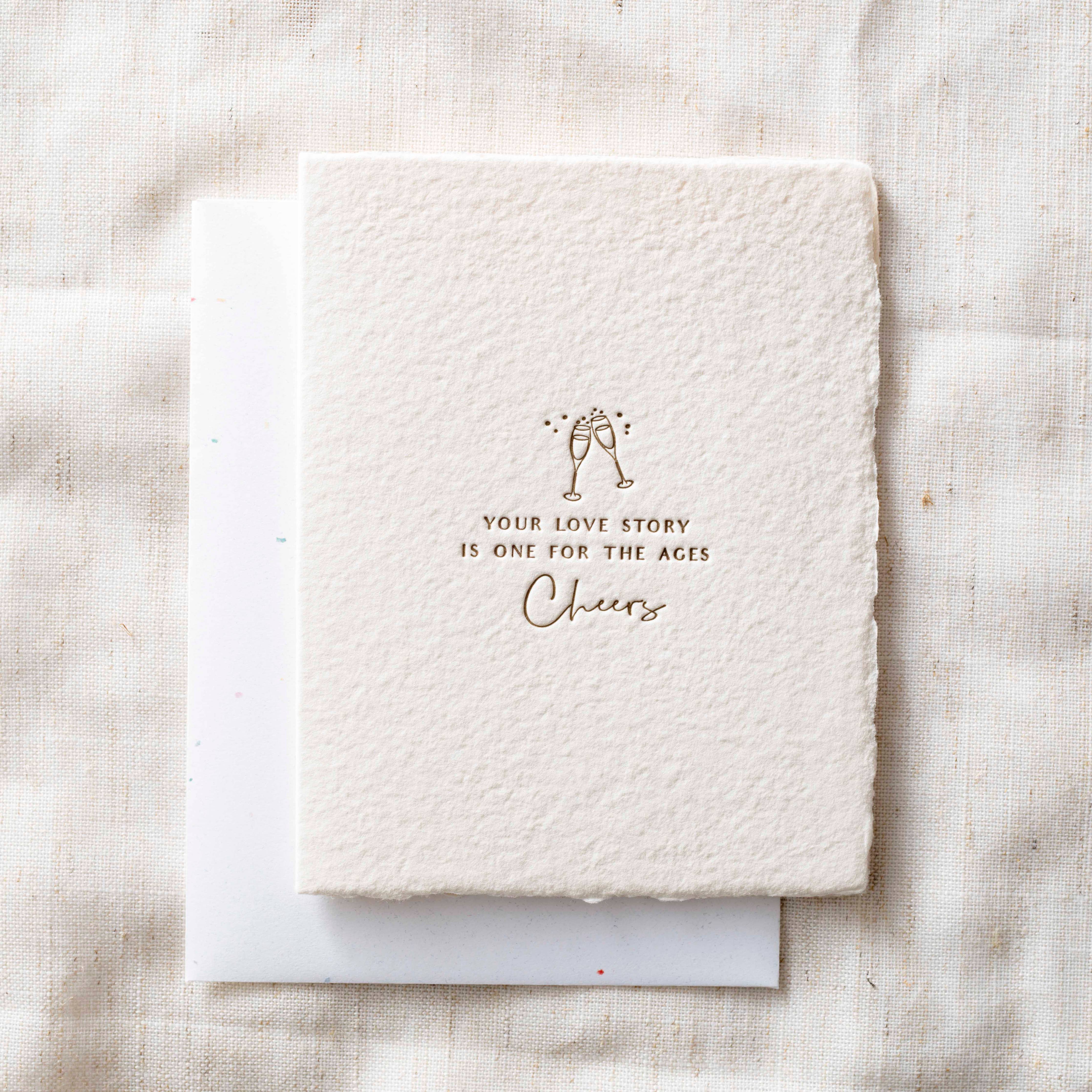 White textured card with gold text and design on a light fabric background