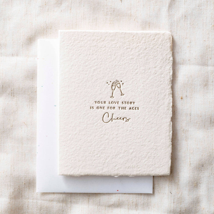 White textured card with gold text and design on a light fabric background