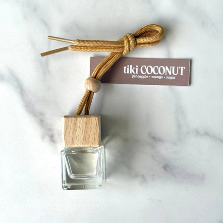 Tiki Coconut diffuser with wooden cap and label on a marble background