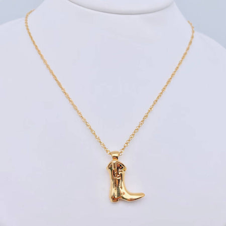 Gold cowboy boot necklace on a mannequin neck against a light gray background