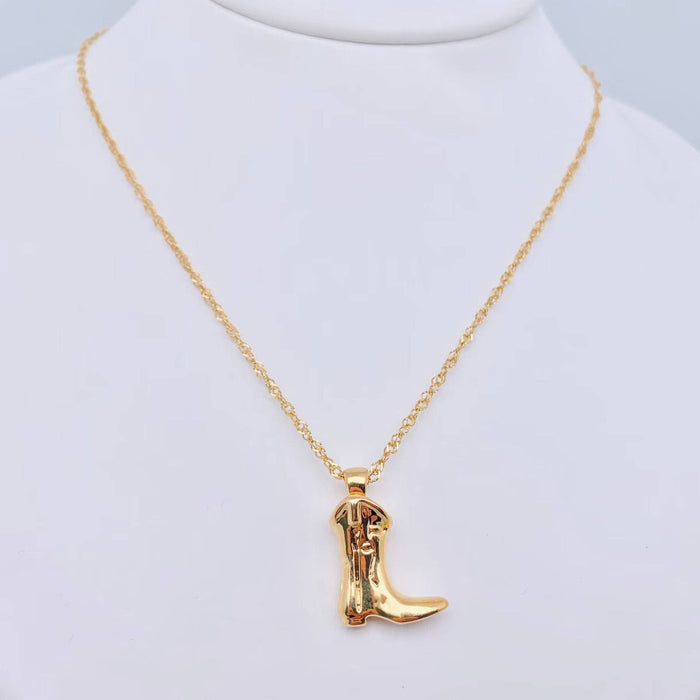 Gold cowboy boot necklace on a mannequin neck against a light gray background
