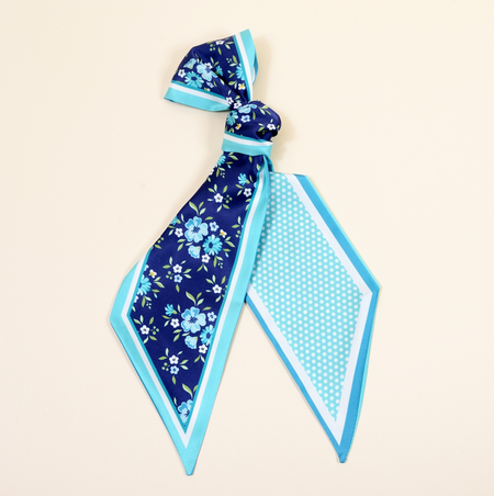 Navy blue floral scarf with a turquoise border on a beige background