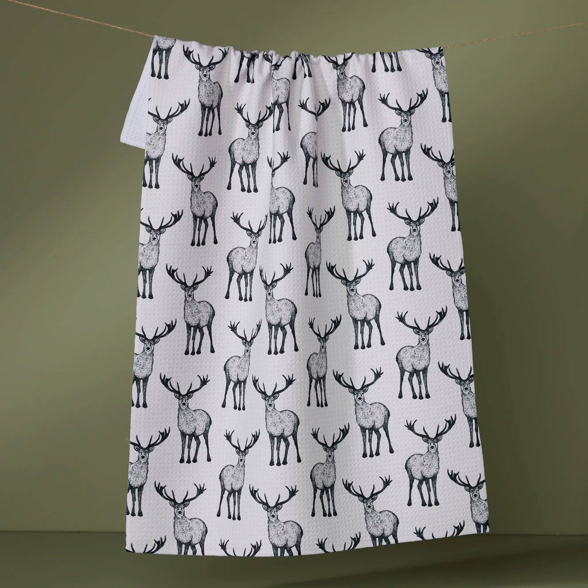 towel with deer pattern hanging on a line against a green background