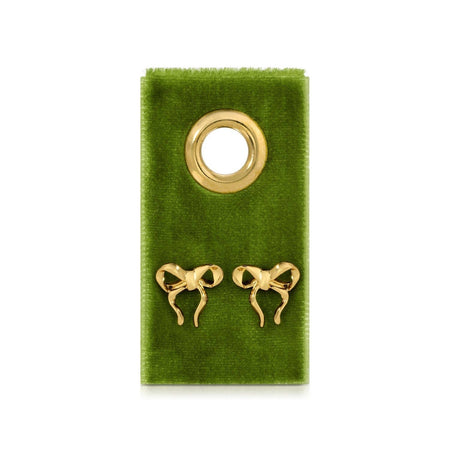 Gold bow-shaped earrings on a green velvet card 
