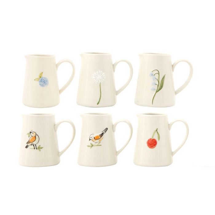 Set of six white creamer holders with nature-themed designs on a white background