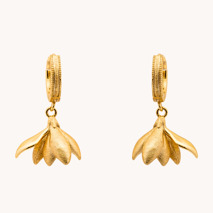 Pair of Magnolia Gold Loops earrings with sculptural brushed gold-tone flower petals hanging from small hoops.