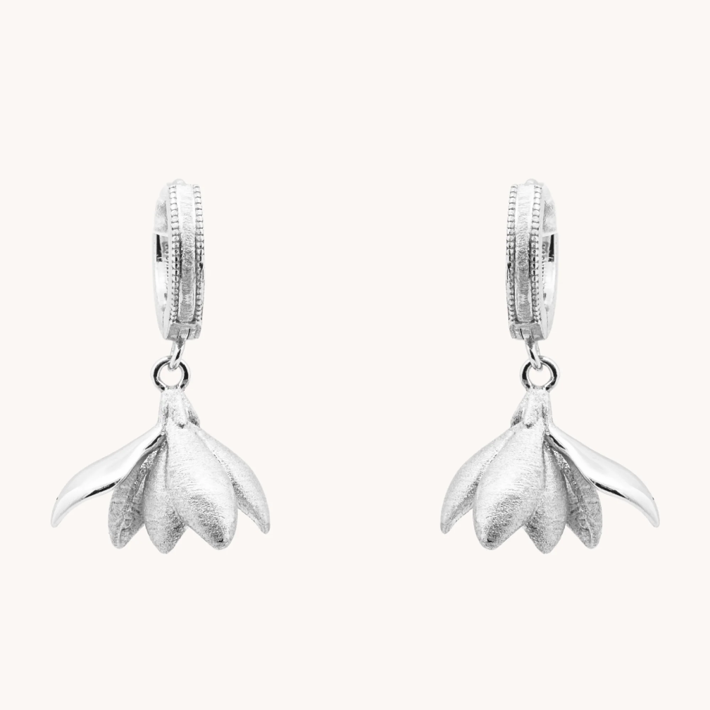 Pair of Magnolia Silver Loops earrings with sculptural silver flower petals hanging from small hoops.