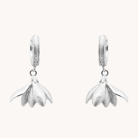 Pair of Magnolia Silver Loops earrings with sculptural silver flower petals hanging from small hoops.