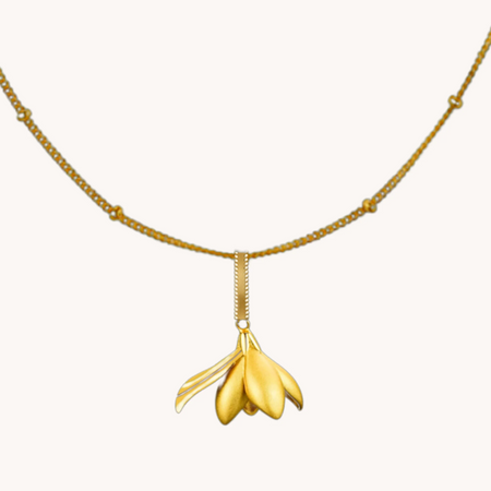 Gold-tone magnolia flower pendant on a delicate chain with spaced bead accents.