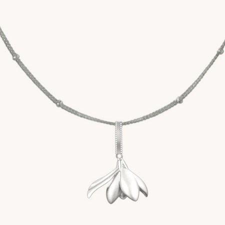 Silver magnolia flower pendant on a delicate chain with spaced bead accents.