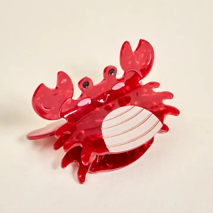 Red crab-shaped claw clip on a beige background