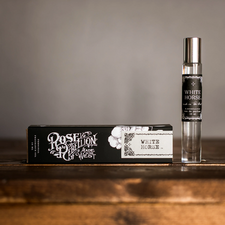 Perfume bottle and packaging labeled 'White Horse' on a wooden surface with a gray background