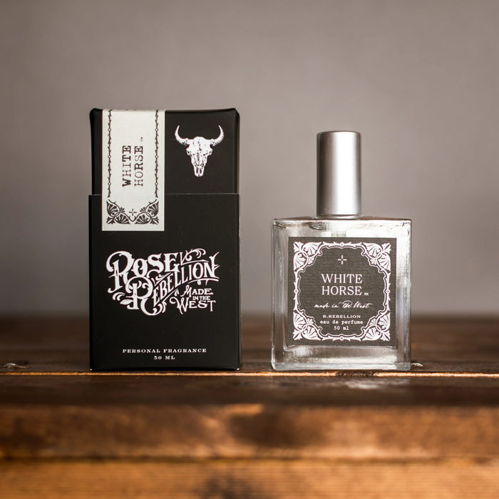 Perfume bottle and packaging of 'White Horse' by Roselion on a wooden surface.