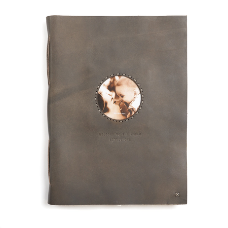 Dark brown/gray leather photo keeper book with the words "Welcome to the world little one" and a circular photo window.