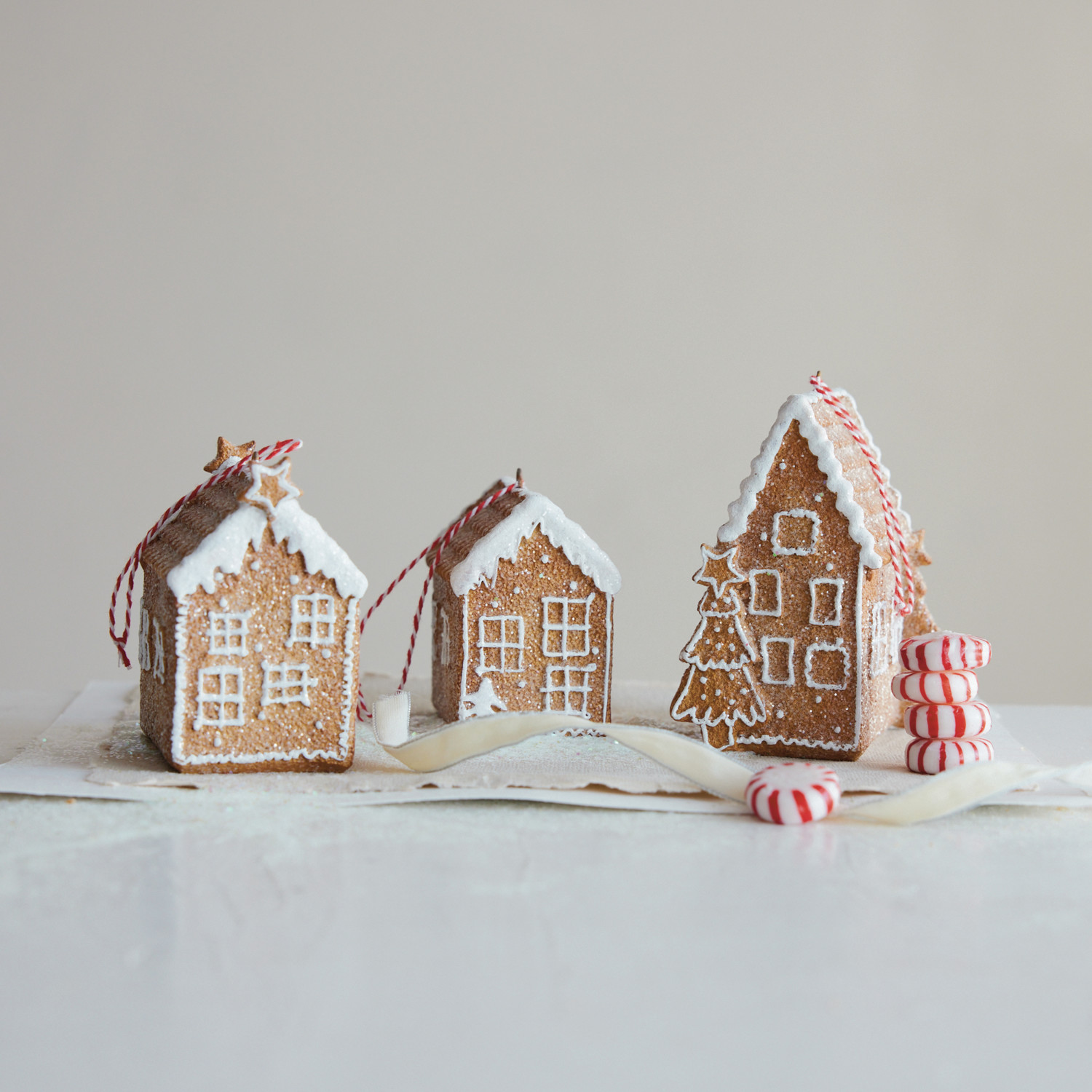 Three small gingerbread houses with candy decorations on a light background