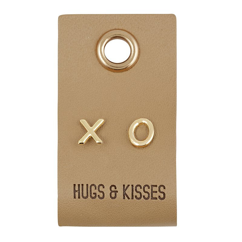 Leather tag with X and O earrings on them. The tag says Hugs & kisses and it is on a white background