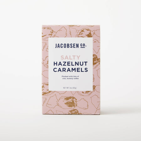 Pink box of salty hazelnut caramels on white background